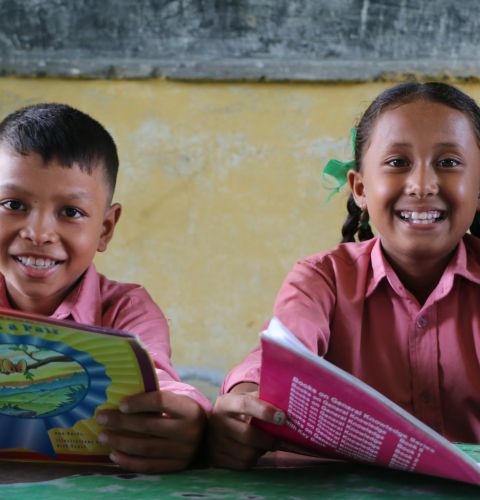Rejina reading books with her friend at their school library in Nepal.