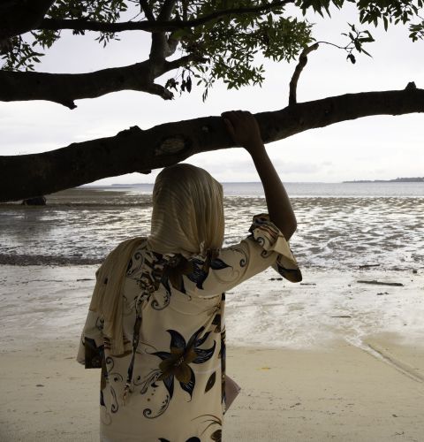 A woman standing with her back to the camera, looking out to the sea