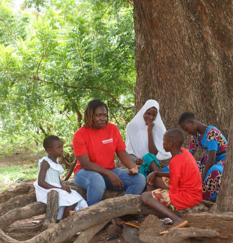 Woman and children sat under a tree