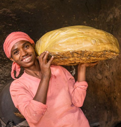 a woman in pink holding a tray of food and smiling