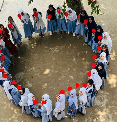 girls standing around in a circle holding heart shaped paper