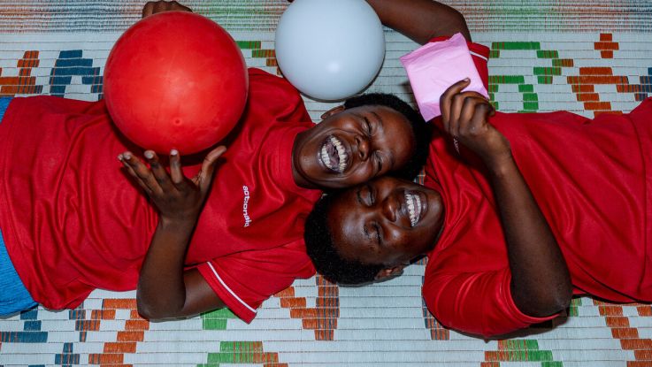 Two girls smiling and laughing playing with red and white balloons