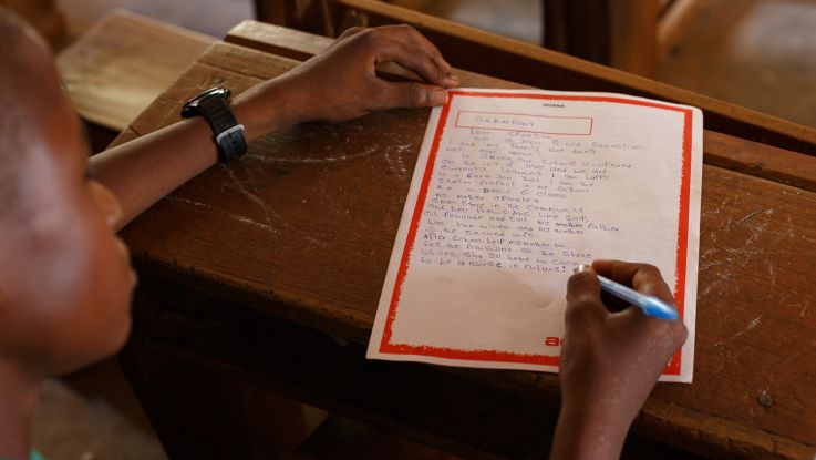 Sabastian, 14, writes a letter in his classroom in Ghana.