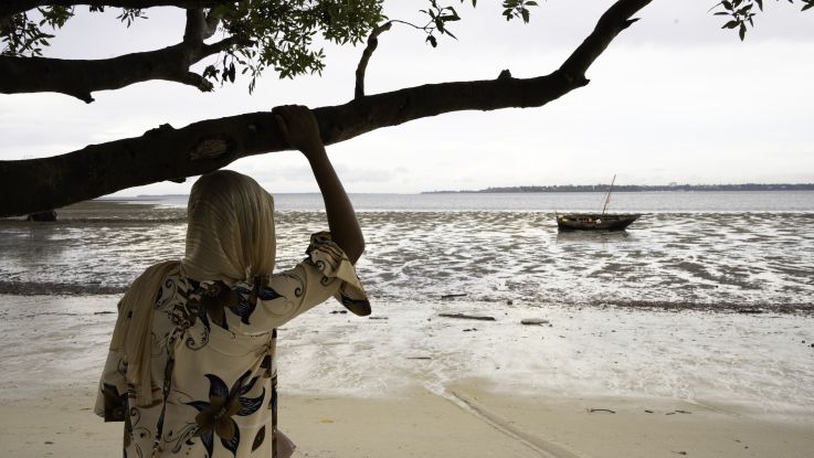 A woman standing with her back to the camera, looking out to the sea
