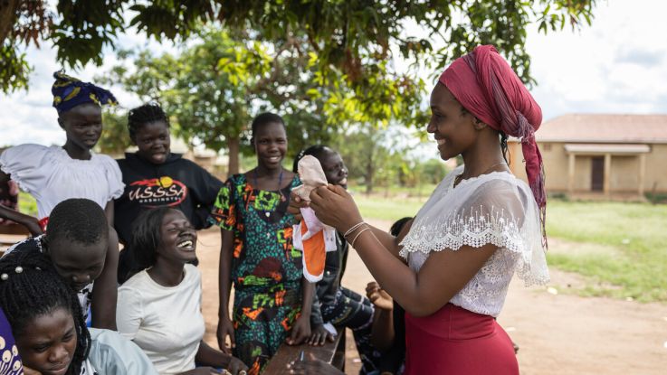 Woman showing girls how to make period pads