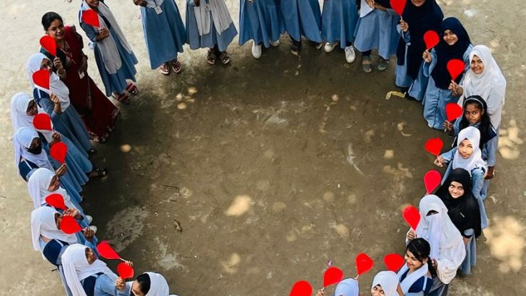 girls standing around in a circle holding heart shaped paper