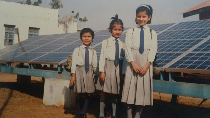 Three young girls standing and posing for the camera in their uniform 