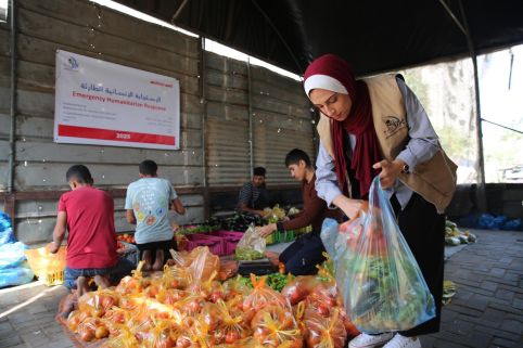 Woman putting vegetables in a bag for distribution in Gaza